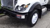 A 2012 International 7400 truck with a shiny front grille large headlights and a prominent wheel showcasing a white rim and black tire