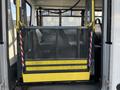 A mobility lift installed in a 2018 Chevrolet Express with a yellow platform and black mesh barrier for wheelchair access