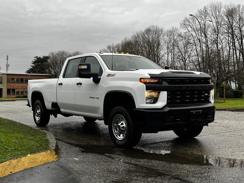 A white 2021 Chevrolet Silverado 3500HD with a black front grille and chrome wheels parked on a wet surface