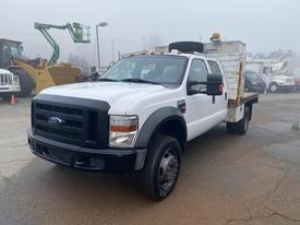 A white 2009 Ford F-450 SD truck with a flatbed and dual rear wheels facing forward