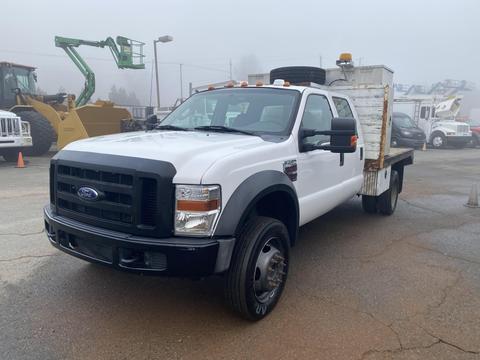 A white 2009 Ford F-450 SD truck with a flatbed and dual rear wheels facing forward