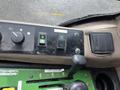 Control panel of a 2014 John Deere 1585 Terrain Cut featuring buttons for various functions and a gear shift lever