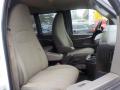 Interior view of a 2011 Chevrolet Express featuring two spacious front seats with beige upholstery and a center console including cup holders