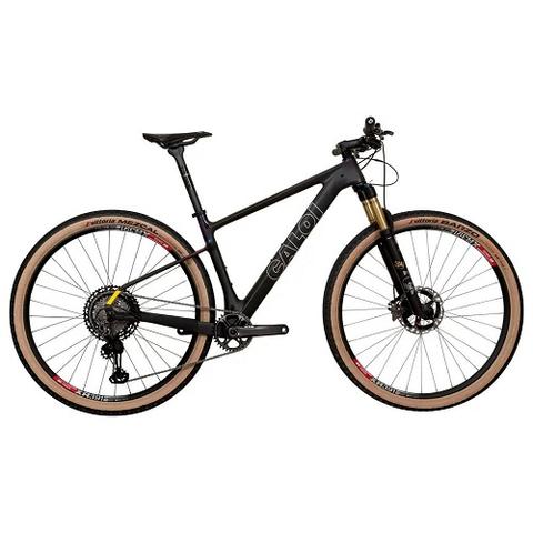 2025 Caloi ELITE CARBON TEAM Mountain Bike featuring a sleek black carbon frame with gold accents and knobby tires designed for off-road performance