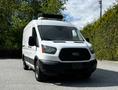 A 2015 Ford Transit van with a white exterior and a black grille parked at an angle with a rooftop unit visible