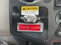 A close-up view of the dashboard of a 2009 Ford F-550 showing a red "DOOR AJAR" warning light and a caution sign about not moving the apparatus when the light is on