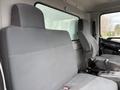 The interior of a 2017 Hino 338 featuring two gray fabric seats with armrests and a gear shift between them