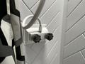 A white shower valve with two knobs mounted on a wall in a camper bathroom