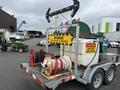 A 2011 Hightliner Aquacide Hot Water Weed Control Dual Flat Deck Trailer with a large tank and two reels for hoses prominently featured on the trailer's deck