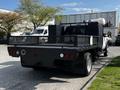 A 2016 Ford F-550 flatbed truck with a black body and a mesh side railing is parked with equipment on its bed and visible rear lights