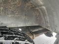 A close-up view of the undercarriage of a 2009 Ford Econoline showing rust and dirt on the metal parts and a black tire partially visible in the foreground