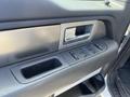 Close-up of the driver's side door panel of a 2014 Ford F-150 showing window controls and a metallic handle