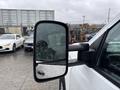 A 2015 GMC Sierra 1500 side mirror with raindrops on the glass reflecting its surroundings