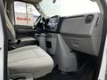 Interior view of a 2014 Ford Econoline showing the front seats and dashboard with controls and a storage area