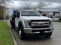 A 2017 Ford F-550 truck with a flatbed and a grille featuring the Ford logo parked on the side of the road