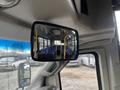 A side mirror view of a 2017 Chevrolet Express showing the interior bus seats and poles for passenger support