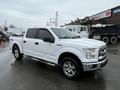 A white 2016 Ford F-150 pickup truck with a crew cab and chrome wheels parked on a wet surface