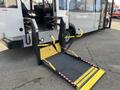 A 2018 Chevrolet Express with a wheelchair ramp extended from the rear entrance showing yellow and black features and textured surface for traction