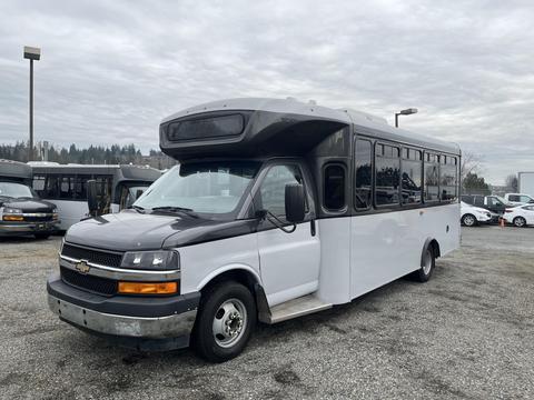 A 2017 Chevrolet Express shuttle bus with a black and white exterior and a large front windshield