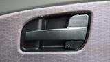 A close-up of a black interior door handle of a 2012 International 7400 with textured grip and surrounding fabric upholstery