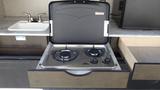 A gas stove with two burners in a pull-out drawer of a 2021 Grand Design Recreational 311BHS camper trailer