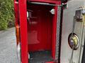 An empty storage compartment of a 1991 Sutphen Deluge fire truck with red interior walls and a textured floor