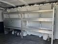 A 2014 Chevrolet Express cargo van interior with metal shelving units installed along one side