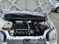 The engine compartment of a 2010 Ford Transit Connect with various components including the air filter battery and coolant reservoir
