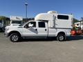 A 2014 Ford F-350 SD in white color with a large camper shell attached to the bed and dual rear wheels