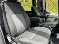 Two black fabric seats inside a 2022 Ford Transit with adjustable armrests and seat controls visible