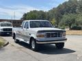 1995 Ford F-250 pickup truck with a white exterior and chrome accents parked in the foreground