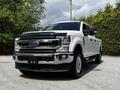 A white 2020 Ford F-350 Super Duty truck is parked with a chrome front grille and headlights visible, showcasing its rugged design and large size