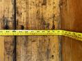 A yellow measuring tape laid out on a wooden surface showing measurements in inches