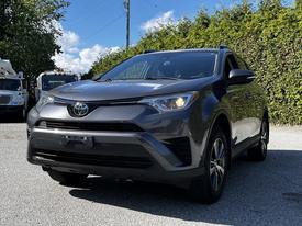 A 2018 Toyota RAV4 with a sleek gray exterior is positioned in the foreground showcasing its modern design and distinctive front grille