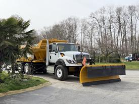 A 2016 International 7600 truck with a mounted yellow snow plow attached to the front