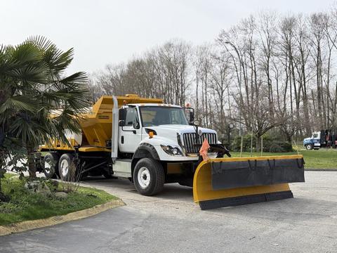A 2016 International 7600 truck with a mounted yellow snow plow attached to the front