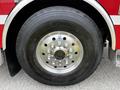 Close-up of a large tire mounted on a fire truck featuring a shiny chrome wheel with multiple bolts and a rugged tread pattern