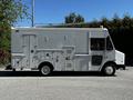 A white 2009 Morgan Olson Workhorse delivery truck with several side doors and compartments is shown from the side