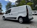 A white 2014 Ford Transit Connect van is parked with its side view visible showcasing its sliding side door and design features