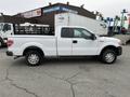 A 2010 Ford F-150 pickup truck in white color with a flatbed and no cargo in the back parked on a lot