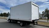 A 2018 Mitsubishi Fuso FE box truck with a white cargo area and black bumper parked on a paved surface