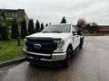 A white 2020 Ford F-350 SD with a black grille and flatbed design parked at an outdoor location