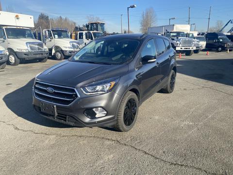 A 2019 Ford Escape in gray with black rims and a sleek design is parked on a concrete surface