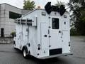 A white 2013 Ford Econoline with a service body featuring multiple utility storage compartments and roll-out equipment racks on the sides