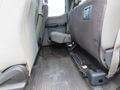 Interior view of the rear seating area of a 2017 Ford F-250 SD showing a folded seat and dark rubber flooring