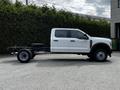 A 2024 Ford F-550 chassis cab in white with a large empty truck bed and black tires visible on the side