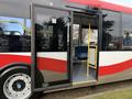 A red and white 2016 Grande West Vicinity bus with an open door revealing empty blue seats and yellow handrails inside
