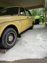 A yellow 1978 Volvo 244 parked on a concrete surface with a partial view of the side and front wheel showcasing its classic design and distinct features