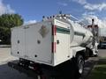 A 2015 Peterbilt 337 vacuum truck with a cylindrical tank and two rear storage compartments designed for waste management and industrial cleaning