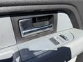 A close-up of the interior door handle and window switch of a 2014 Ford F-150